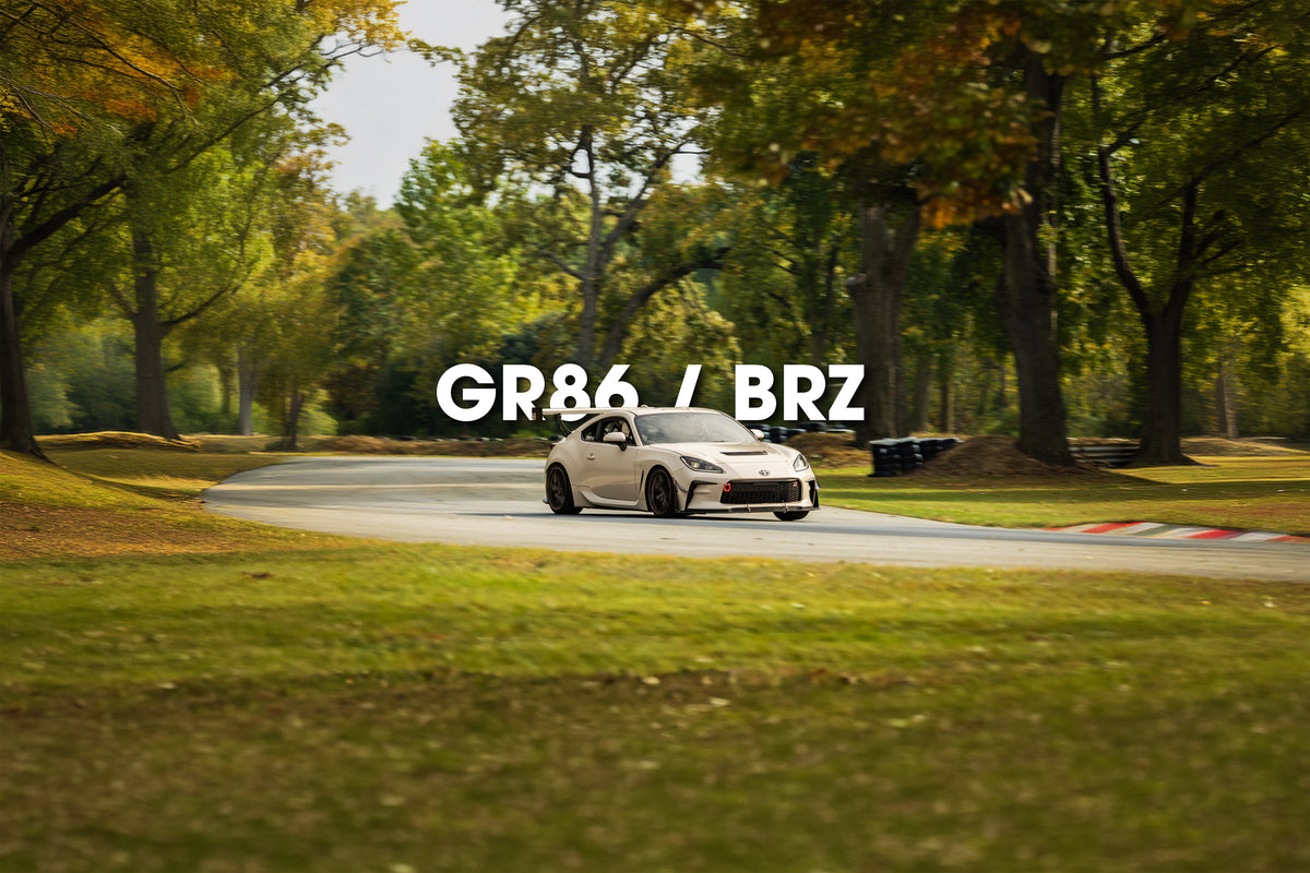 Toyota GR86/BRZ with rear wing on a tree-lined track
